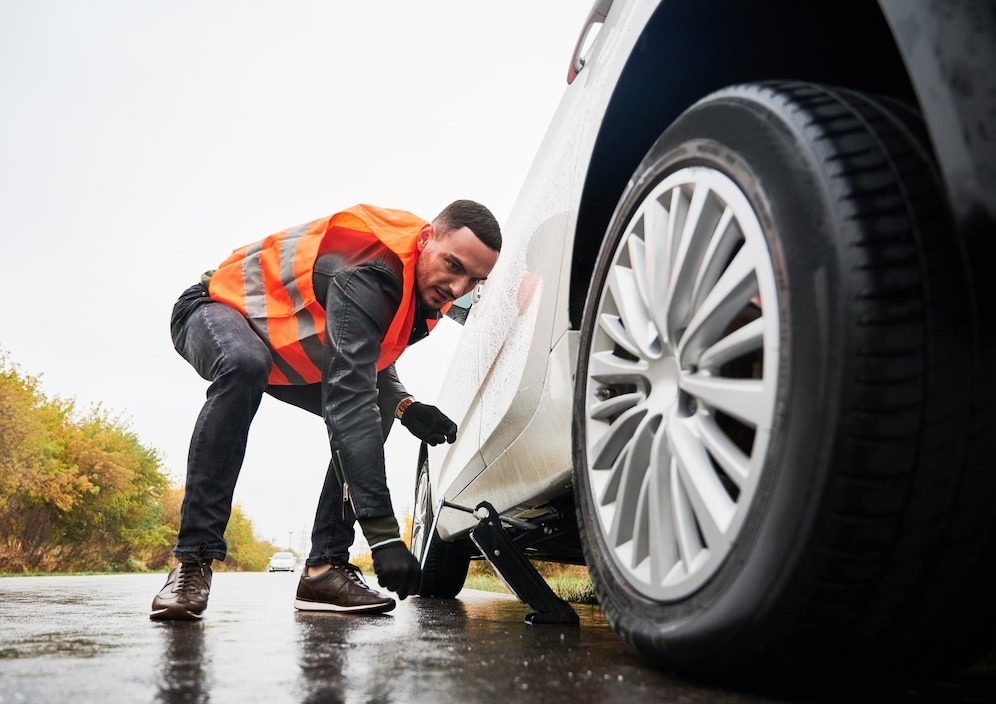 stopped white car with punctured car tire on a roadside